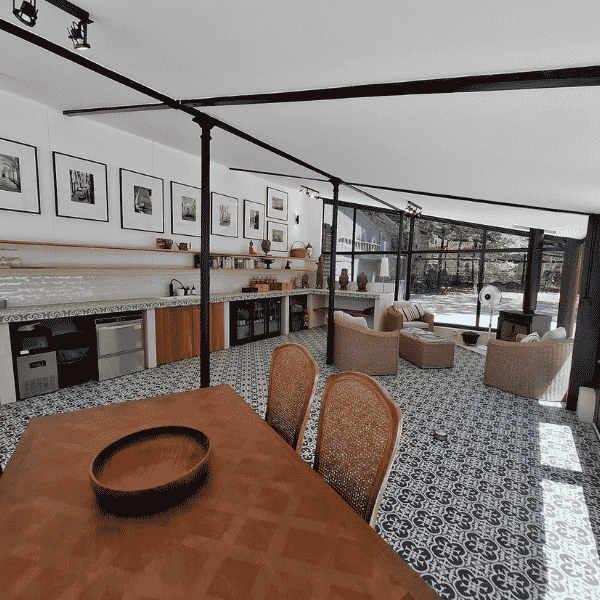 Modern open-plan kitchen and living room with patterned tiled floor, large windows, wooden furniture, wall art, and natural light filling the space.